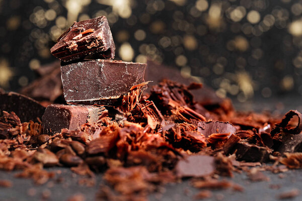 Разбитый темный шоколад, какао-порошок и кофейные зерна на деревянном столе
