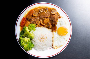 Siyah ahşap zemin üzerine köri pilavı (Onsen tamago, Patates, enoki mantarı, soğan, brokoli, Japon tarzı)