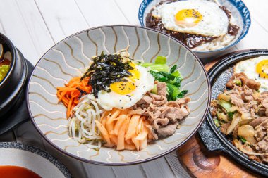 Bibimbap, üzerinde sebze, kimchi, biber ezmesi ve yumurta ve dilimlenmiş et bulunan bir kase sıcak beyaz pirinç olarak servis edilir.