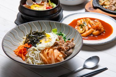 Bibimbap, üzerinde sebze, kimchi, biber ezmesi ve yumurta ve dilimlenmiş et bulunan bir kase sıcak beyaz pirinç olarak servis edilir.