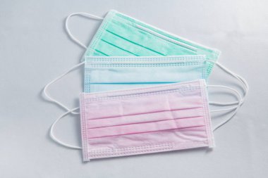 Pembe, yeşil ve mavi tıbbi yüz maskesi ve beyaz arka planda izole edilmiş Corona virüsü koruması, covid-19