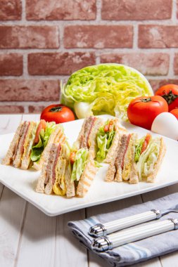 Kahvaltı, sandviç, yumurta, sebze ve içeceklerle birlikte masada.