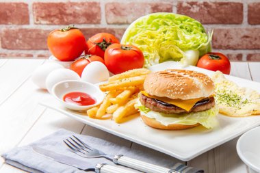 Sığır peynirli burger, yumurta, sebze ve içeceklerle kahvaltı.