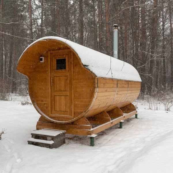 Bir kış ormanının arka planında banyo fıçısı. İlk kabarık kar yağıyor. Sağlık hizmetleri
