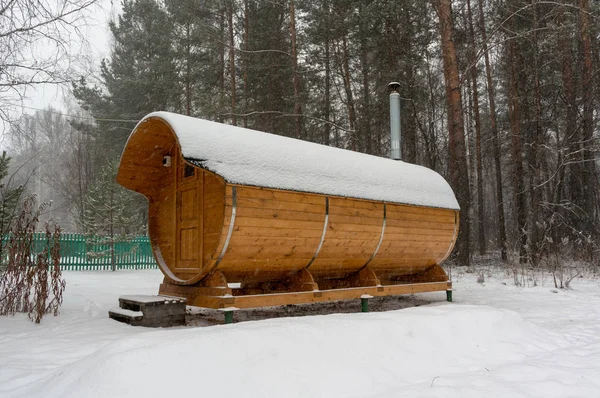 Bath barrel on the background of a winter coniferous forest. The first  snow is falling. Health care