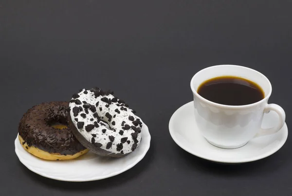 Donuts de chocolate e café. Dois belos donuts saborosos em um pires e uma xícara de café quente aromático — Fotografia de Stock