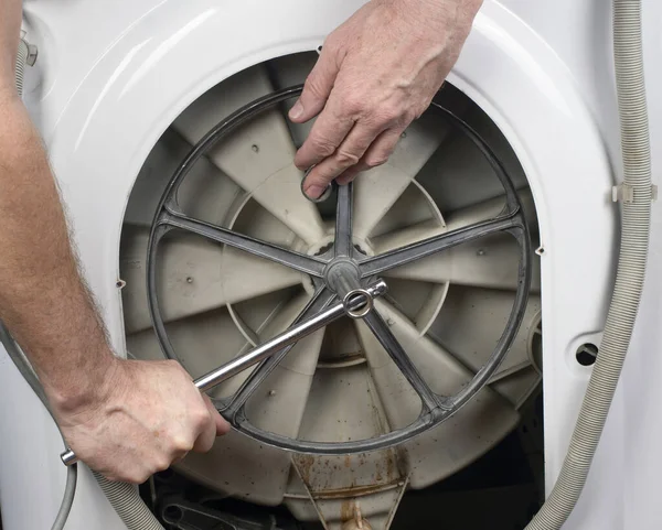 Repair of washing machines, repair of large household appliances. Plumber removes parts from a washing machine