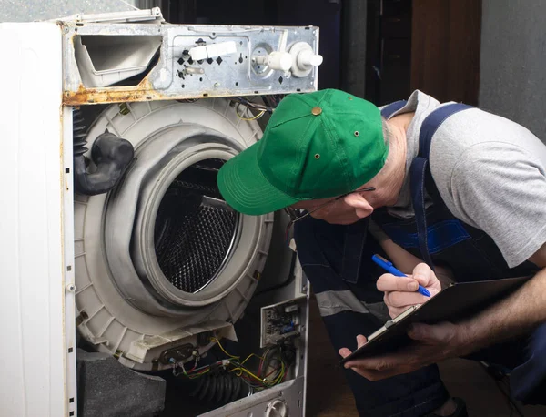 Çamaşır makinelerinin tamiri, büyük ev aletlerinin tamiri. Bir teknisyen eski bozuk bir çamaşır makinesini inceliyor ve arızaları tespit ediyor.
