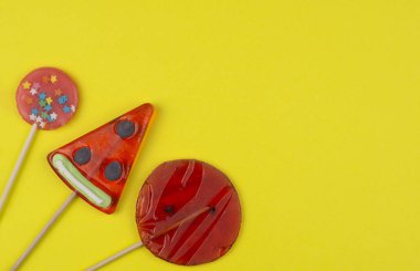 Tatlı tatlı şeker lolipoplar sarı arka planda parlak kırmızı bir daire üzerinde yatıyordu.