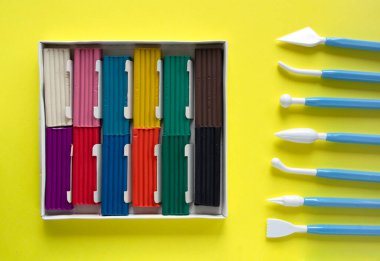 Sarı zemin üzerinde on iki parça farklı renk ve kil yığını olan büyük bir kutu.