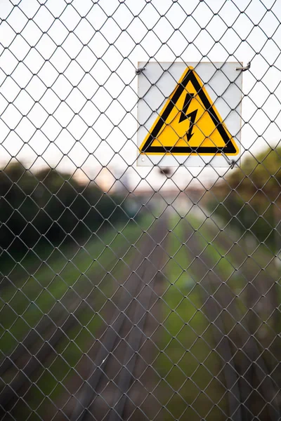 The yellow sign of high voltage over the railroad — 스톡 사진