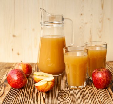 Olgun elmalar ve taze sıkılmış meyve suyu. Tahta bir masanın üzerinde.