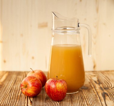 Olgun elmalar ve taze sıkılmış meyve suyu. Tahta bir masanın üzerinde.