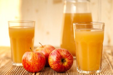 Olgun elmalar ve taze sıkılmış meyve suyu. Tahta bir masanın üzerinde.