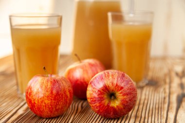 Olgun elmalar ve taze sıkılmış meyve suyu. Tahta bir masanın üzerinde.