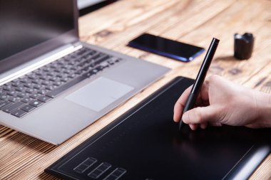 Tasarımcının işyeri, erkeklerin elleri grafik tableti üzerinde çalışıyor. Yakın plan..