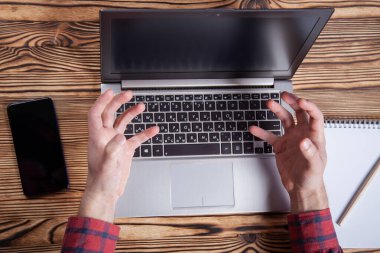 İş yeri, erkek eli dizüstü bilgisayarda yazıyor. Üst görünüm.