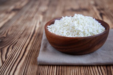 Ahşap masada süzme peynirli ahşap kase. Sağlıklı ürün..