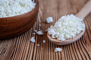 Ahşap tabakta süzme peynir ve kaşık var. Sağlıklı ürün..