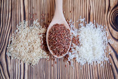 Ahşap zemin üzerinde farklı pirinç türleri. Beyaz, kahverengi ve kırmızı.