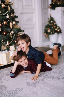 Oynayan ve gülümseyen yakışıklı çocuklar. Evde Noel ağacının yanında komik çocuklar var ve birlikte eğleniyorlar.