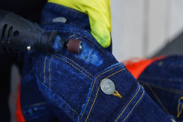 The aging process of a denim jacket, the master in rubber gloves, causes scuffing and damage to the fabric.