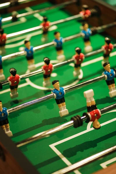 Foosball, miniature plastic players of blue and red teams against each other. Entertainment and games.