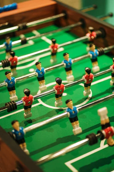 Foosball, miniature plastic players of blue and red teams against each other. Entertainment and games.