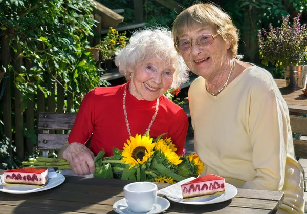 Vrouwen met zonnebloemen eten taart — Stockfoto