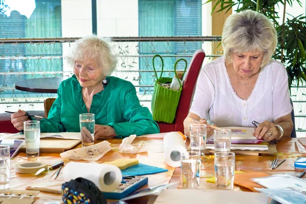 Äldre kvinnor målning vid bord — Stockfoto