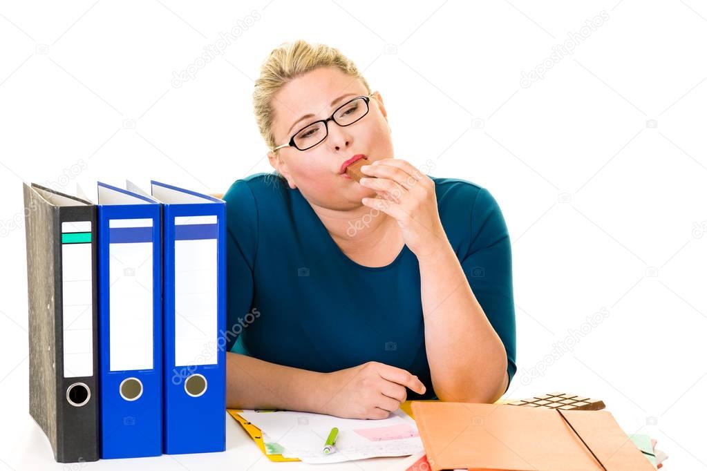 Overweight businesswoman eating chocolate