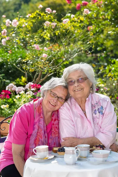 Çay bahçesinde oturan iki neşeli üst düzey kadın