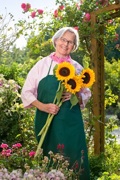 Uśmiechający Się Starszy Kobieta Gospodarstwa Słoneczniki Ogrodzie Słoneczny Dzień — Zdjęcie stockowe