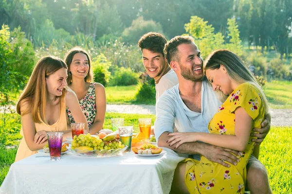 公園で楽しいピクニックをしている若者 カップルがいちゃつくと恋に落ちる お友達がカップルを見て笑って — ストック写真