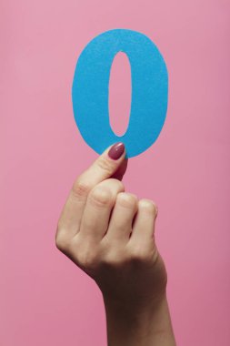 2020 yılının bir parçası olarak sıfır numarayı gösteren kadın elleri, renkli pembe arka planda mukavva figür.