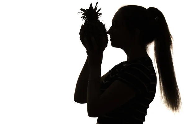 パイナップルの香りを楽しむ女性のシルエット白の孤立した背景に鼻の近くにエキゾチックな果物を持つ女の子 コンセプトビタミンと健康食品 — ストック写真
