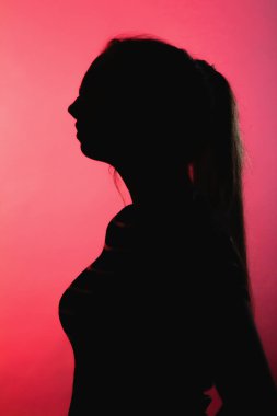 Kırmızı ışıklı arka planda düşünceli bir kızın silüeti tanınmaz bir kadın yüzü, konsept duygular, stres.