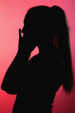 Kırmızı ışıklı arka planda korkmuş bir kızın silueti, tanınmayan kadın yüz profili, konsept duyguları, stres, tehlike