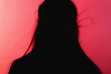 Kırmızı arka planda dağınık saçlı siluet kadın figürü, tehlike kavramı ve garip