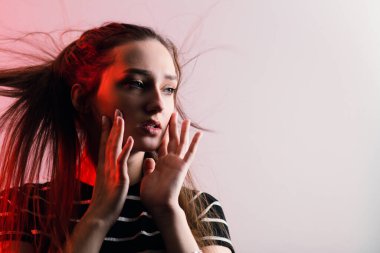 Güzel, şehvetli bir kızın portresi makyajlı ve uzun saçlarıyla stüdyo kırmızı arka planında, konsept güzellik ve moda