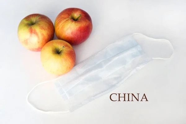 Apples and protective respiratory mask on a white background, fruit from China.