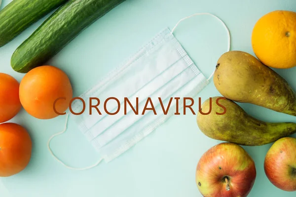 Fruits, vegetables and protective mask on a mint background, harvest of fruits and vegetables, protection from coronavirus, fruits from China. Close-up, top view, flat lay.