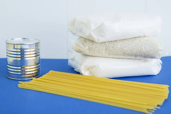 Food aid during quarantine. Products: sugar, rice, pasta, canned food. Food donation on a blue background. Help with food for coronavirus.