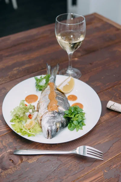 Dorado fish, baked in the oven. Fish with greens and white wine. Cooking at home, home cooking. Gourmet food - grilled fish and wine