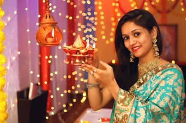 Diwali festivalini kutlayan geleneksel sari elbiseli güzel bir Hintli kadının portresi. Dekoratif arka planda Diwali, Stüdyo portresi vesilesiyle..