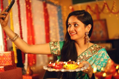 Diwali Stüdyo portresi vesilesiyle dekoratif arkaplanlı geleneksel diwali festivalini kutlayan Hintli genç güzel bir kadının portresi..