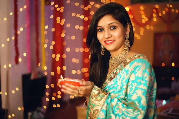 Diwali festivalini kutlayan geleneksel sari elbiseli güzel bir Hintli kadının portresi. Dekoratif arka planda Diwali, Stüdyo portresi vesilesiyle..