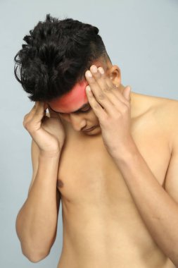 Genç adam acı içinde başını tutuyor. Tıbbi konsept