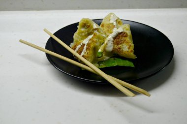 Hamur üçgeni şeklinde bir yemek, içinde sebze dolgusu olan yemek, sos ile doldurulur.