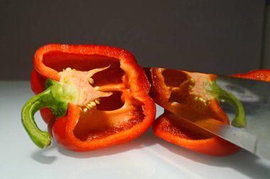 Kırmızı dolma biber, tahta saplı bir bıçakla ikiye bölünmüş.